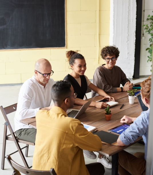 A group of people sitting around a table talking and smiling while doing so